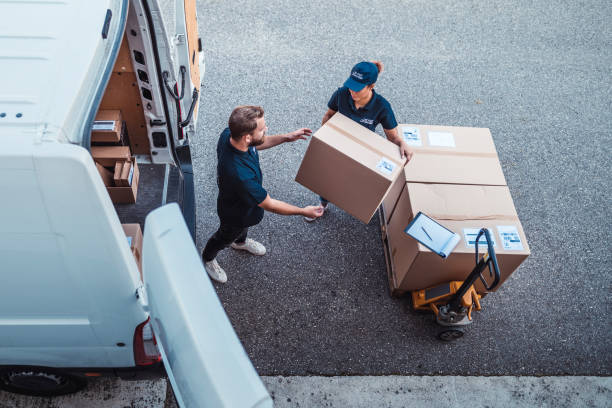 delivery workers using a hydraulic hand pallet truck to load a delivery van.